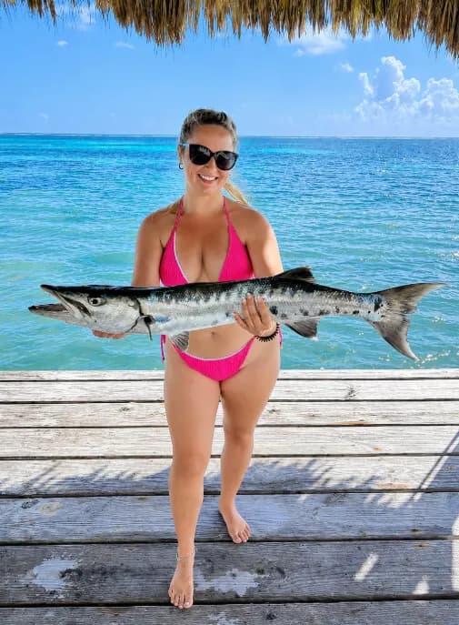 A guest holding up a barracuda on the pier