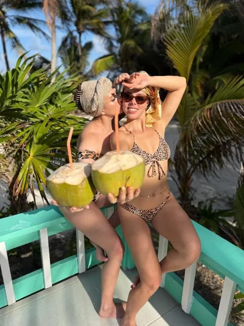 Two friends laughing with fresh coconuts on the veranda