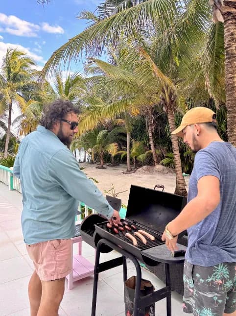 Two guests grilling on the pool deck under the palms