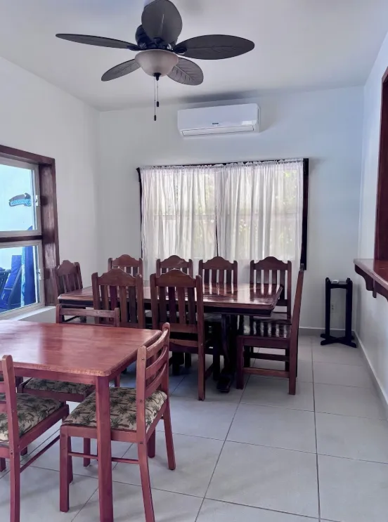 A wooden dining table and chairs beside a curtained window